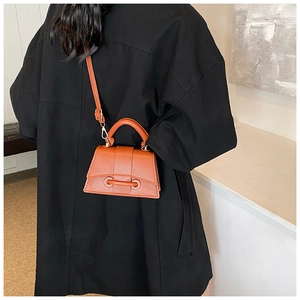 Détail d'un mini sac à main caramel grainé avec poignée supérieure et bandoulière réglable