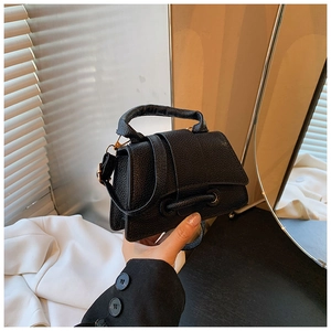 Détail de la texture cuir grainé noir et finitions dorées de ce sac à main carré