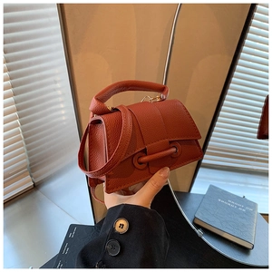 Détail du mini sac à main rouge brique en cuir grainé avec poignée et bandoulière