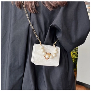 Detail of white marble mini bag featuring pearl handle and golden heart pendant