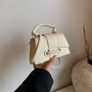 Mini sac à main blanc crème avec motif litchi et boucle en cuir tenu en main