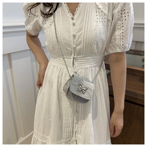 Detalle de mini bolso plateado con hebilla de mariposa 3D y correa de cadena fina
