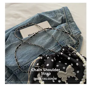 Polka dot bucket bag with elegant pearl handle and silver butterfly pendant detail