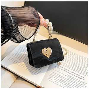 Close-up of black pleated mini bag with heart gold buckle and pearl handle detail