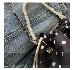 Detail of silver hardware hooks on a black polka dot pearl chain shoulder bucket bag