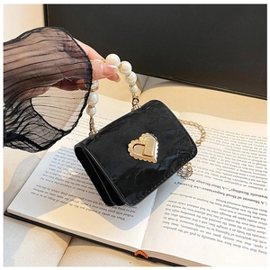 Close-up of black velvet mini bag with golden heart lock and elegant pearl handle