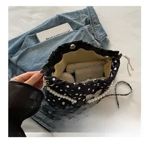 Polka dot bucket bag showing internal capacity with pearl strap and chain detail