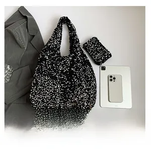 Detail view of black sequin tote bag set with matching coin purse on a minimalist desk