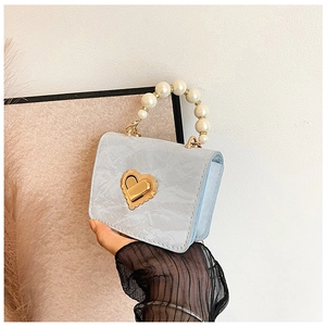 Detail of light blue mini bag with marble texture, pearl handle and heart lock