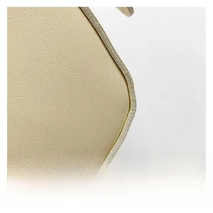Close-up of beige leather texture with lychee grain and precise stitching on bag edge