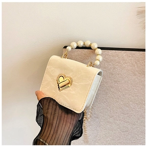 Detail of elegant cream marble-texture mini bag with pearl handle and gold heart clasp