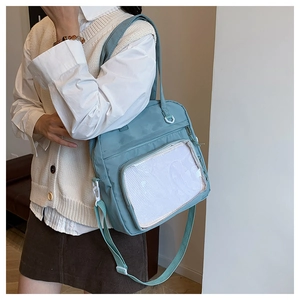 Detail view of light blue nylon crossbody bag with white mesh pocket on a female model