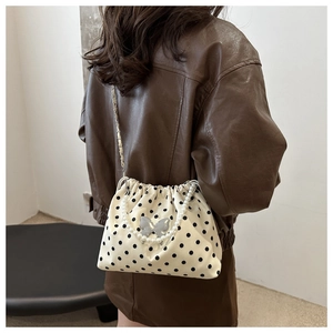 Polka dot bucket bag with pearl handle and metal chain shown on model's shoulder