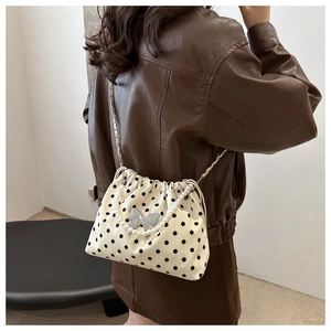 Detailed view of polka dot bucket bag with pearl chain and silver butterfly charm