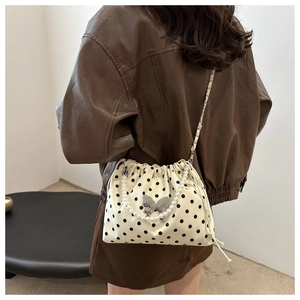 Close-up of polka dot bucket bag featuring silver butterfly clasp and pearl handle
