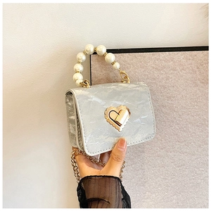 Detail of silver pleated handbag with pearl handle and golden heart twist lock