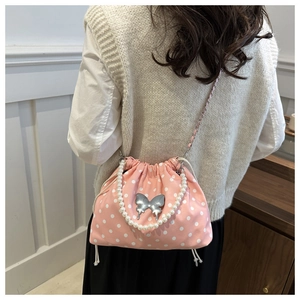 Polka dot pink bucket bag with pearl handle and silver chain shown on model back