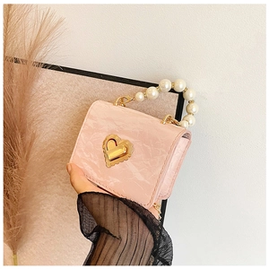 Detailed macro view of pink marble texture leather mini bag with gold heart clasp and pearls