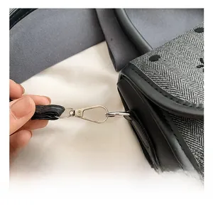Close-up of silver metal hook and herringbone fabric texture on a stylish handbag