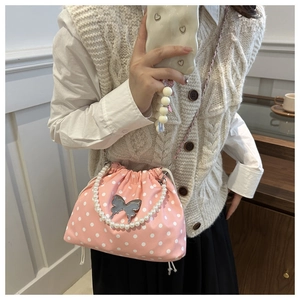 Pink polka dot bucket bag with pearl handle and silver butterfly charm detail on model