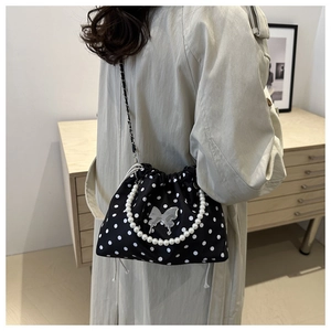 Polka dot bucket bag with large pearl handle and metal butterfly detail on model