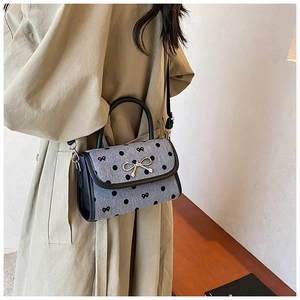 Detail of retro grey polka dot bag with bow print and golden metal clasp on beige coat
