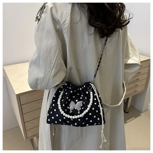 Polka dot bucket bag with pearl handle and butterfly buckle detail on model