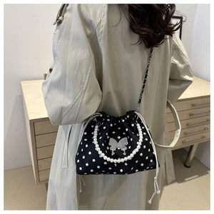 Lifestyle view of a polka dot bucket bag with pearl handle and silver butterfly charm