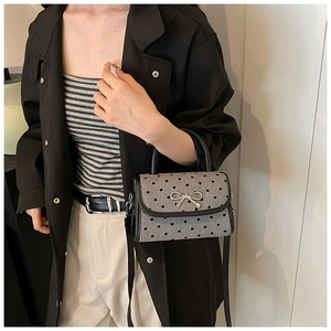 Detail of grey textured fabric mini bag with heart dots and silver metal bow decoration