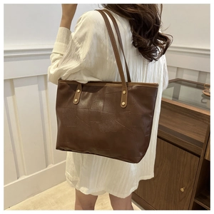 Dettaglio borsa tote marrone scuro in ecopelle con patchwork geometrico su modella