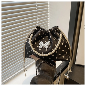 Detail of black polka dot bucket bag with silver butterfly and pearl handle