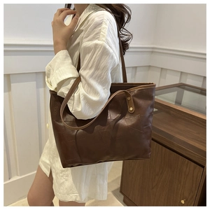 Dettaglio della borsa tote marrone scuro con patchwork irregolare e spalline sottili