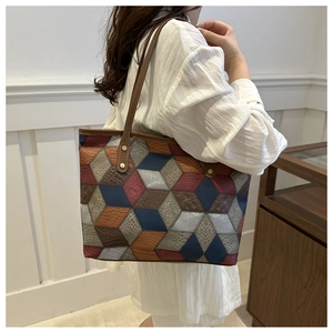 Dettaglio borsa tote con patchwork geometrico in pelle testurizzata e rivetti dorati