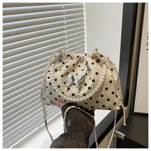 Detailed view of white polka dot bucket bag with silver butterfly and pearl handle