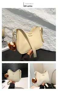 Dettaglio della borsa a secchiello beige con logo dorato e ciondolo in peluche