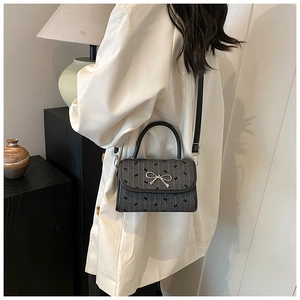 Detail view of a gray crossbody bag with bow patterns and silver metal buckle