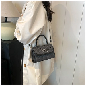 Detail of grey and black crossbody bag featuring bow print and silver metal buckle
