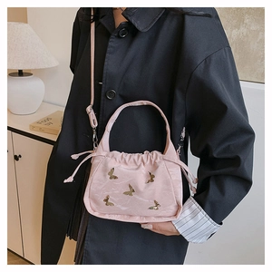 Detailed view of pink pleated handbag with gold butterfly accents and drawstring closure
