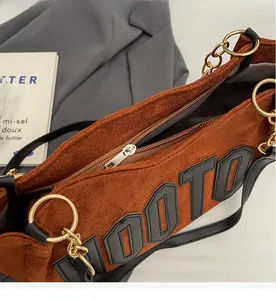 Detail of brown suede tote bag featuring smooth zipper and gold chain metallic ring hardware