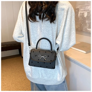 Model wearing a black polka dot crossbody bag with a silver metallic bow decoration