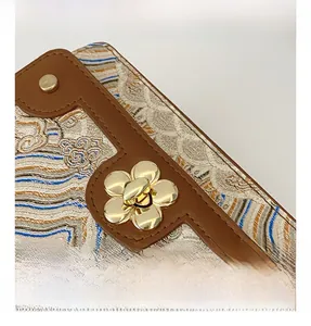 Detail of the golden flower twist lock and textured jacquard fabric on a retro handbag
