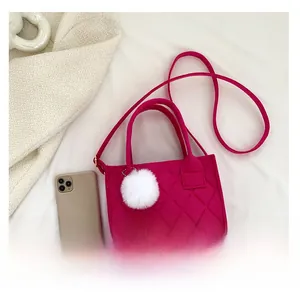 Detail der rosaroten Filzhandtasche mit Rautensteppung und weißem Plüsch-Bommel-Anhänger