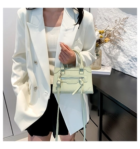 Chic light green crossbody bag held by a model in a minimalist stylish interior setting