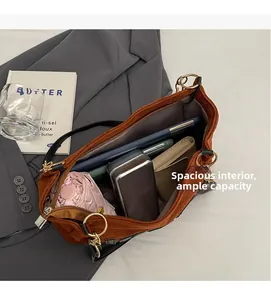 Detail showing the large capacity of the brown suede tote bag with daily essentials inside