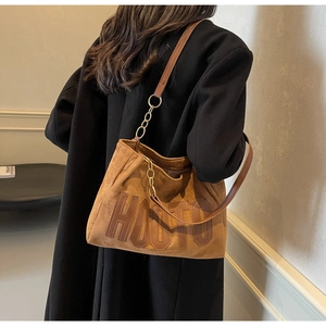 Detail of brown suede tote bag with HOUTO leather patch and chain strap