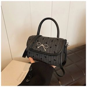 Detail of black crossbody bag with silver bow accent and cute cat silhouette pattern