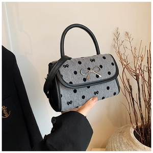 Detail of the bow-tie metal buckle and polka dot pattern on the fashion handbag