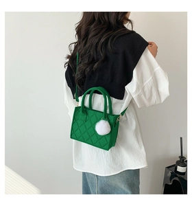 Grüne Filztasche mit Rautensteppung und weißem Bommel an einem weiblichen Model