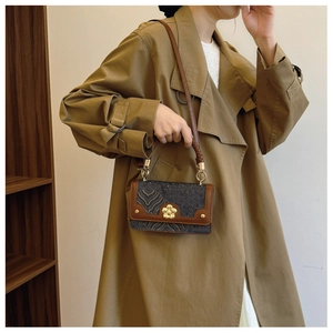 Detail of vintage square handbag showing floral gold clasp and woven handle texture