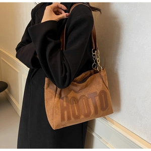 Detail of brown faux suede tote bag with HOOTO leather patch and gold chain strap